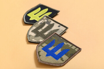 Different military badges of Ukrainian army with trident on beige background