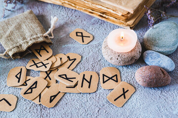Scandinavian ancient runes for fortune telling, a bag, a candle and stones on the table
