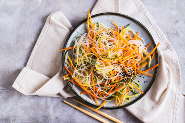 Close up of appetizing salad of funchose, carrots, cucumber and sesame on a plate  top view