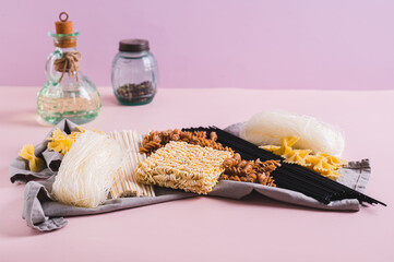Different types of pasta and noodles made from wheat, rice and buckwheat on a cloth on the table
