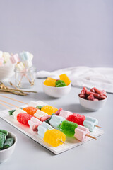 Gummy candy kabobs on skewers served on the table vertical view
