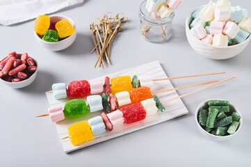 Marmalade candies-kebabs and marshmallows on skewers on the table
