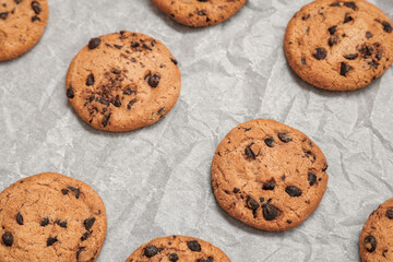 Sweet cookies with chocolate chips on baking paper, closeup