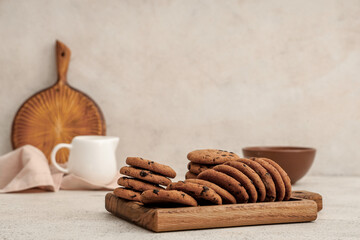 Wooden board of sweet cookies with chocolate chips on white background