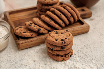 Wooden board of sweet cookies with chocolate chips on white background