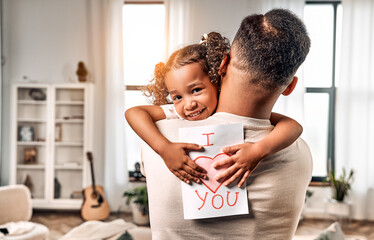  Happy beautiful little girl holding greeting card gift for dad on father's day in dad's arms....