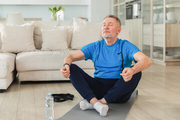 Yoga mindfulness meditation. Senior adult mature man practicing yoga at home. Mid age old grandfather sitting in lotus pose on yoga mat meditating relaxing. Older man doing breathing practice