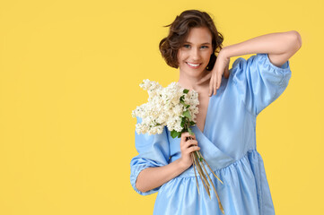Beautiful young woman with bouquet of blooming white lilac flowers on yellow background