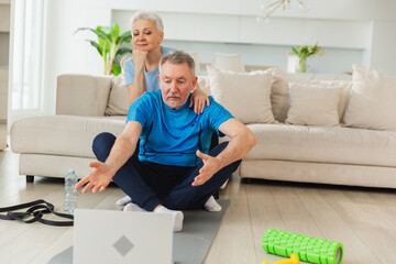 Yoga mindfulness meditation. Senior adult mature couple practicing yoga with online lessons in...