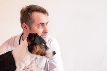 Treatment and vaccination of domestic animals.A veterinarian holds a dog in his arms. Vet clinic. White background, copy space