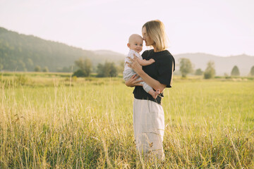 Mother and baby. Concept of natural maternity and motherhood. Beautiful woman and little baby happy together in green nature background. Loving mom with child outdoors.
