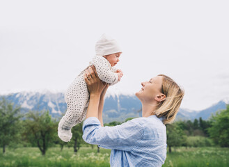 Mother and baby walking on nature outdoors. Family in green nature background. Loving woman with...
