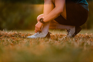 A sporty man tying running shoes preparing for a run or workout at the park active lifestyle.