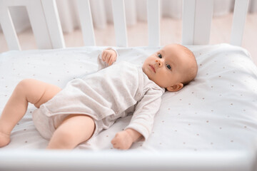 Cute little baby lying in crib at home