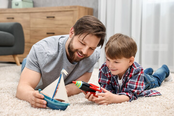 Happy dad and son playing toys together at home