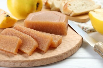 Tasty sweet quince paste, fresh fruits and knife on white wooden table, closeup