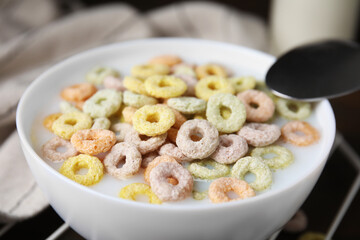 Cereal rings and milk in bowl on table, closeup