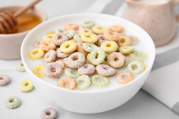 Cereal rings and milk in bowl on white table, closeup