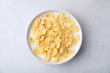 Breakfast cereal. Corn flakes and milk in bowl on light grey table, top view