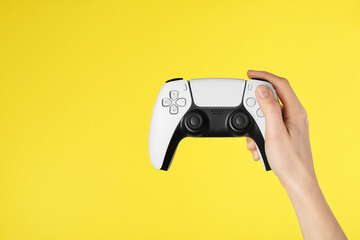 Woman with game controller on yellow background, closeup. Space for text