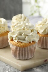 Tasty cupcakes with vanilla cream on grey table, closeup