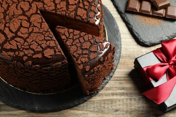 Delicious truffle cake, chocolate pieces and gift box on wooden table