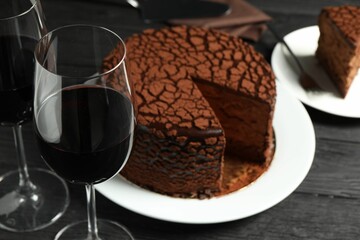 Delicious chocolate truffle cake and red wine on black wooden table