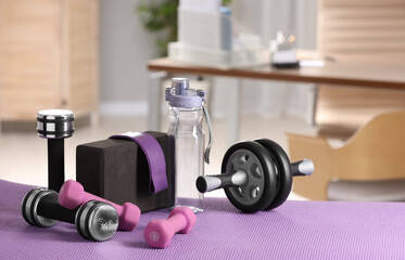 Many different sports equipment on mat indoors