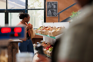 Female client of african american ethnicity exploring eco friendly store and choosing different...