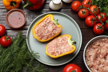 Raw stuffed peppers with ground meat and ingredients on wooden table, flat lay