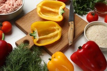 Raw stuffed peppers with ground meat and ingredients on white marble table, above view