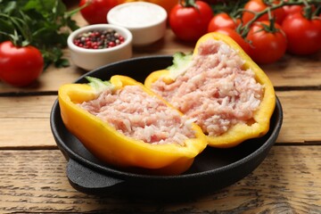 Raw stuffed peppers with ground meat and ingredients on wooden table