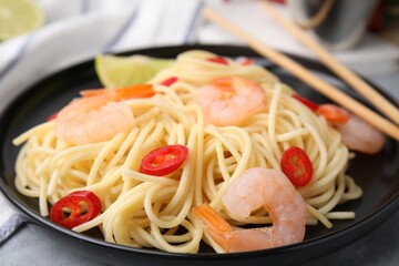 Tasty spaghetti with shrimps and chili pepper on grey table, closeup