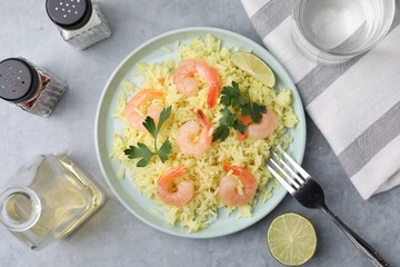 Delicious risotto with shrimps, lime and parsley served on light grey table, flat lay