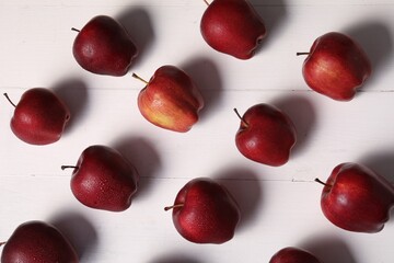Fresh red apples with water drops on white wooden table, flat lay