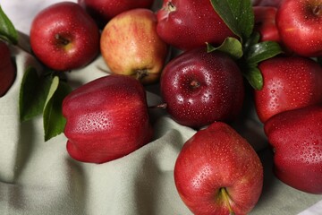 Ripe red apples with leaves and water drops on table