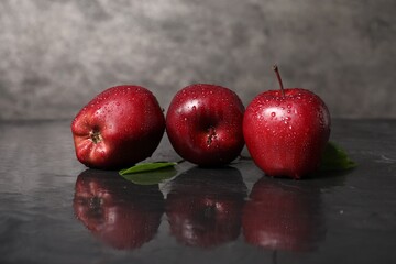 Wet red apples on dark grey table