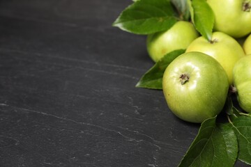 Ripe green apples with leaves on dark grey table, closeup. Space for text
