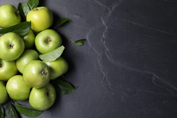 Ripe green apples with leaves on dark grey table, flat lay. Space for text