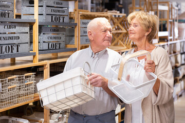 Focused senior woman and man looking for storage basket at household store