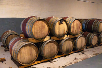 Oak wine barrels stacked on top of each other aging in a wine cellar. 