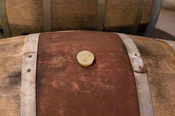 Close up on the top of an old wooden oak barrel with wine. Center is the Wood Bung Plug to seal the opening of the barrel 