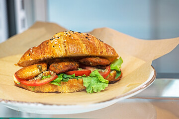 hot croissant with pieces of meat, tomato, lettuce. Quick snack