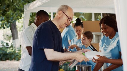Friendly volunteers offering hunger relief to poor and needy individuals. People of different...