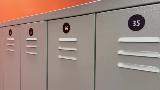 Gray lockers with numbers for people's clothes in the gym locker room. Close-up
