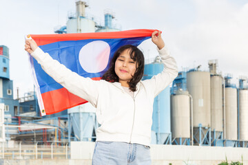 Cheerful asian girl with laotian flag standing in front of factory
