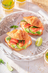 Tasty and hot french croissant with fish and avocado.