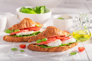 Hot and homemade french croissant with cheese, tomatoes and basil