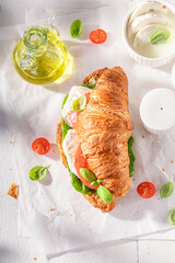Fresh and golden french croissant with cheese, tomatoes and basil