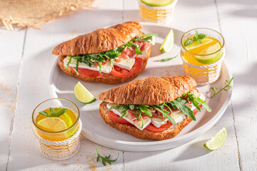 Healthy and hot french croissant with prosciutto, camembert and arugula.
